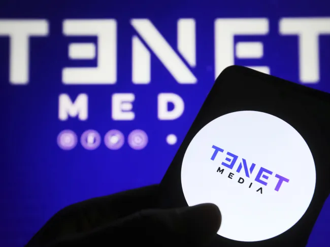 In this photo illustration, a Tenet Media logo is seen on a smartphone and on a pc screen.